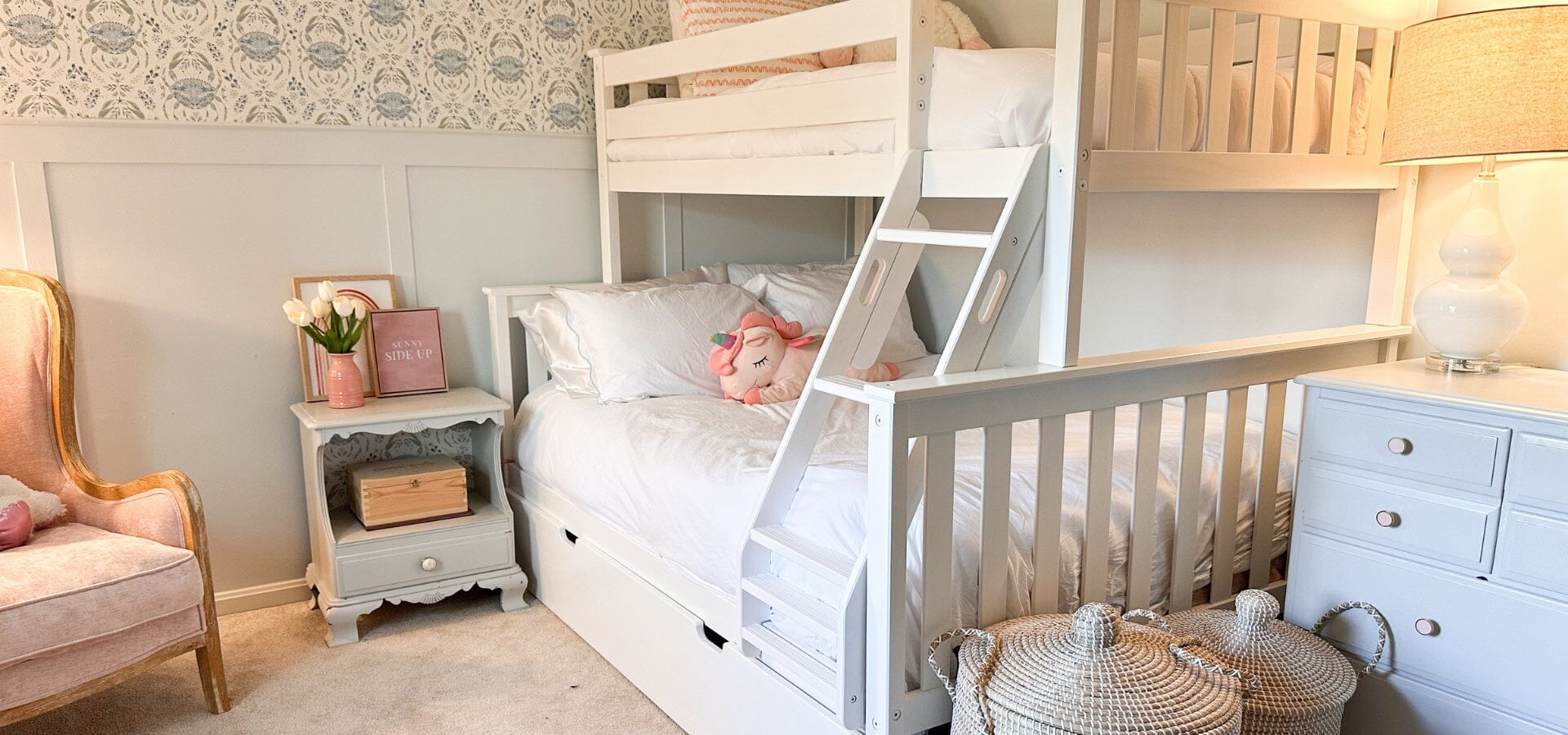 White twin over full bunk bed with trundle, pink chair, baskets, blue nightstands, and blue crab wallpaper