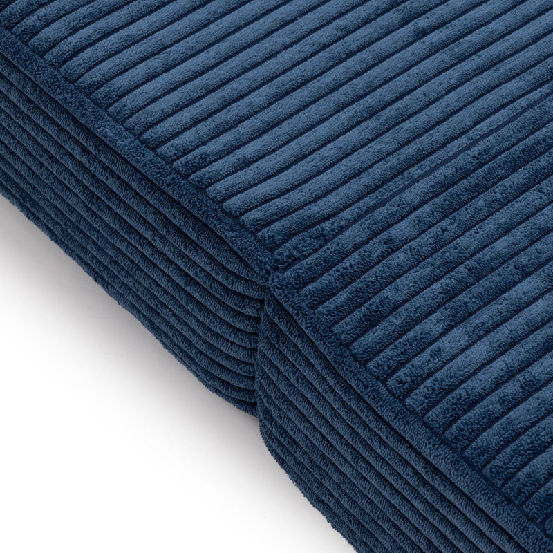 Close-up of a navy blue ribbed corduroy cushion showing plush textured fabric for sofa throw pillow and home decor