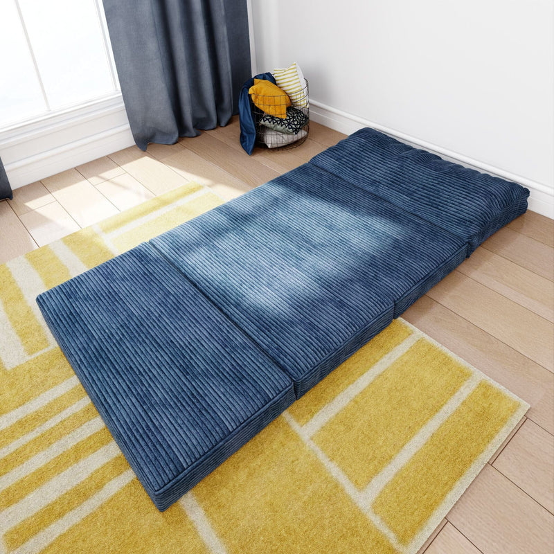 Blue corduroy tri-fold floor mattress on yellow geometric rug in sunlit minimalist living room — portable guest bed