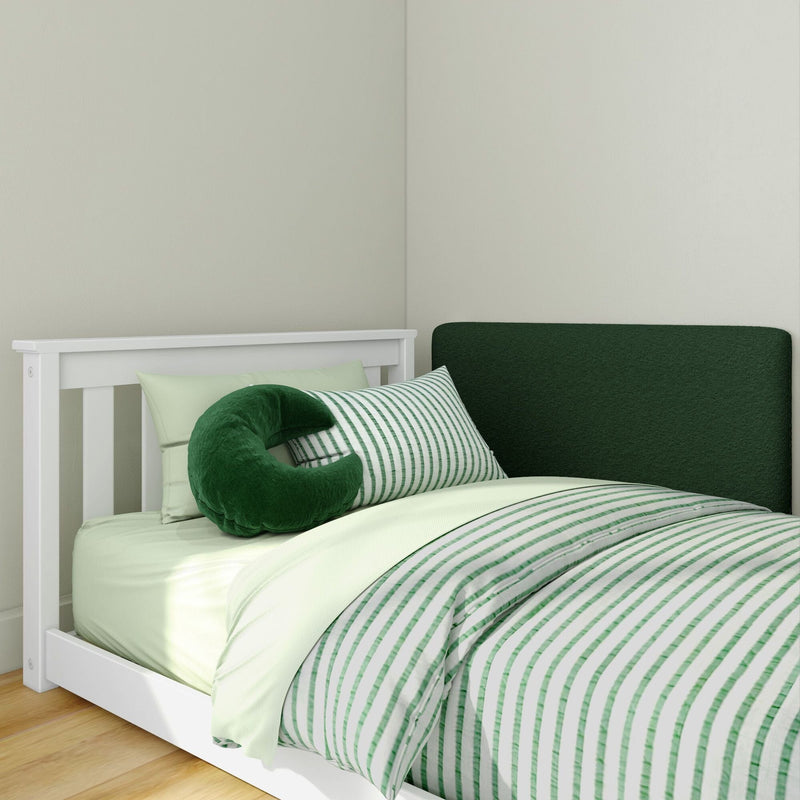 White wood twin bed styled with green striped duvet, mint sheets, dark green upholstered headboard and plush crescent pillow in a minimalist bedroom