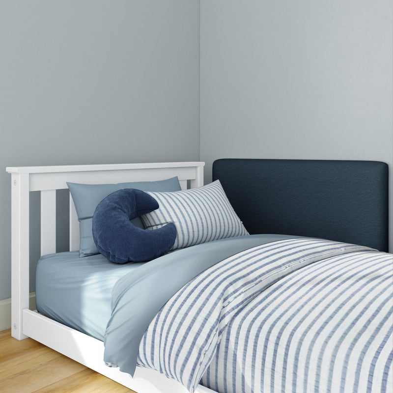White-frame twin bed with blue striped duvet, light-blue sheets and pillows, navy crescent neck pillow in a minimalist coastal-style bedroom