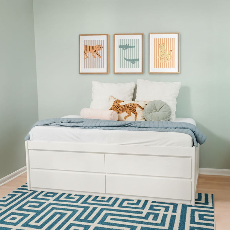 Kids bedroom featuring white storage bed with drawers, blue geometric rug, mint green walls and three framed animal prints above a tiger pillow
