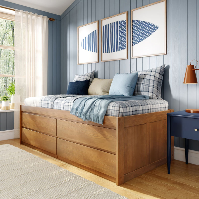 Cozy coastal bedroom with wooden platform bed and storage drawers, plaid blue pillows, light-blue shiplap walls and triptych blue artwork