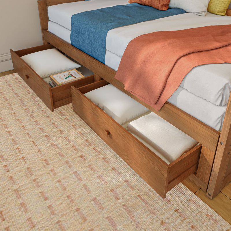 Wooden trundle bed with under-bed storage drawers open, white mattresses and blue and coral bedding — space-saving bedroom storage solution