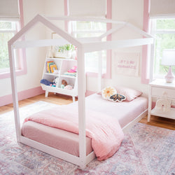 Child's bedroom with pink bedding and house-frame bed, featuring playful decor and a cozy atmosphere.