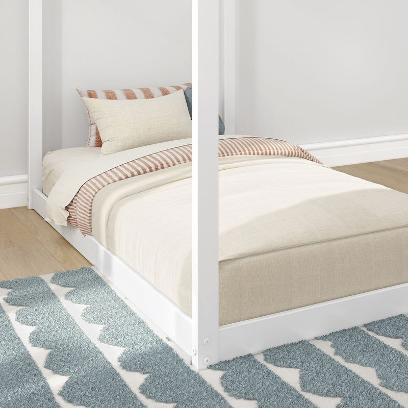 Modern minimalist bedroom featuring a cozy white bed with striped bedding and blue geometric rug.