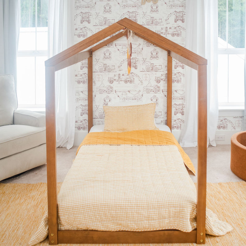 Cozy children's bedroom with a wooden house-frame bed and construction-themed wallpaper.