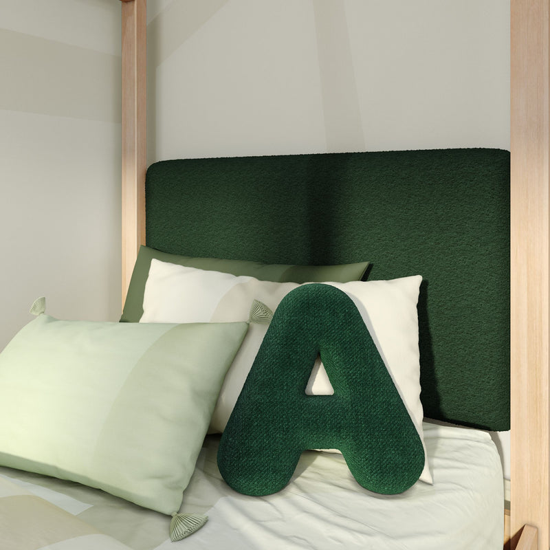 Close-up of green upholstered headboard with large green "A" pillow, light green decorative pillows and natural wood bed frame in a modern cozy bedroom