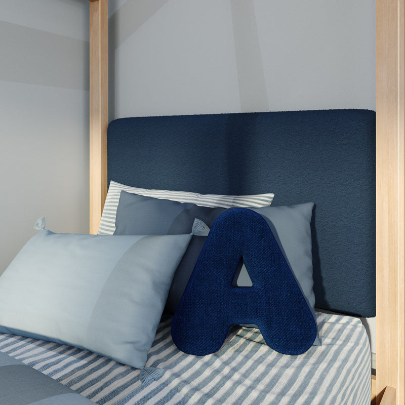Modern navy upholstered headboard and natural wood bed frame with striped blue bedding, layered decorative pillows and navy letter "A" cushion