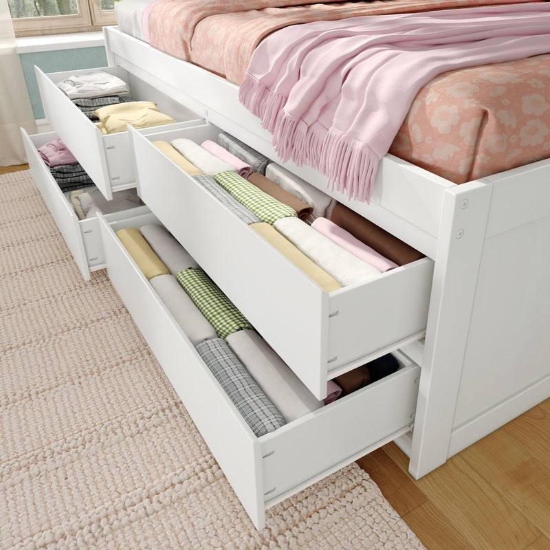 White wooden platform bed with built-in pull-out under-bed storage drawers neatly organized with folded clothes, pastel pink bedding and fringed throw