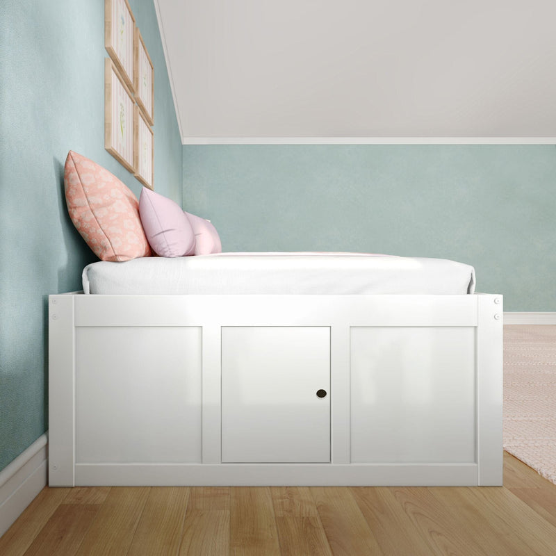 White wooden storage bed with pastel pink and peach pillows against a mint green wall and framed art in a cozy kids' bedroom nursery