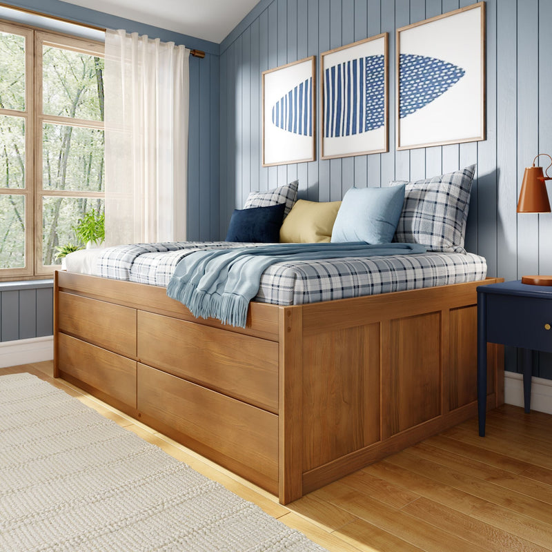 Cozy bedroom interior with natural wood storage bed, plaid bedding, layered throws and decorative pillows against a blue paneled accent wall