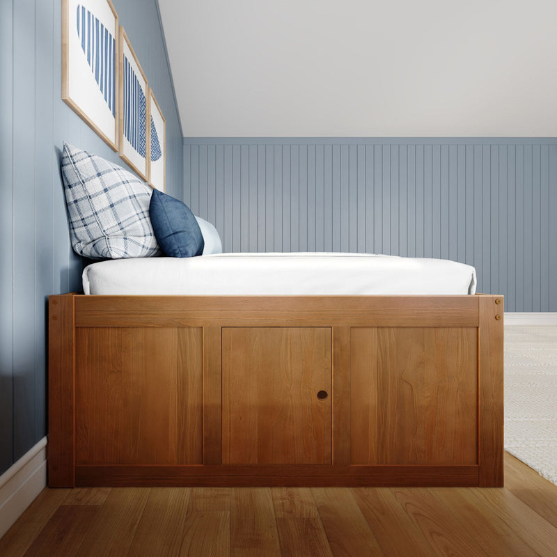 Modern coastal bedroom interior with a wooden platform bed, white bedding, blue plaid and navy pillows, light-blue vertical wainscoting and framed blue artwork