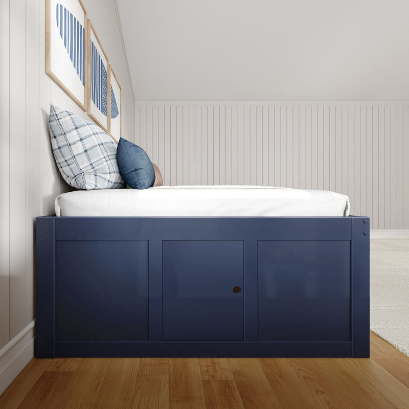 Navy blue bed frame with white mattress and blue plaid pillows against white beadboard wall with framed blue-striped art