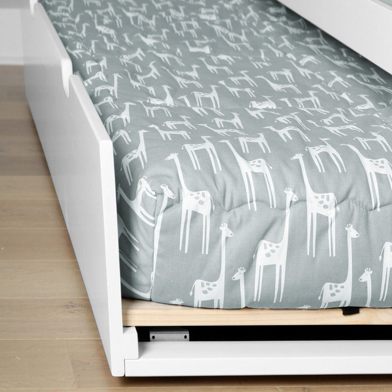 Gray fitted crib sheet with white giraffe pattern on a white wooden toddler bed frame, nursery bedding close-up