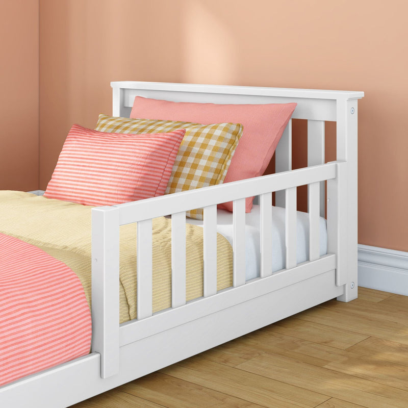 White wooden toddler bed with guardrail, pink striped pillows and yellow gingham cushion in peach nursery