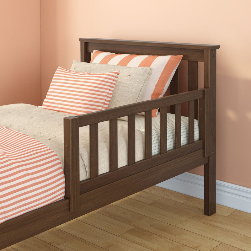 Modern dark wood twin bed frame with coral-and-white striped pillows and duvet against a peach wall on hardwood floor