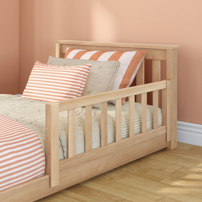 Natural wood toddler bed frame with peach striped pillows and neutral linen bedding in modern kids' bedroom