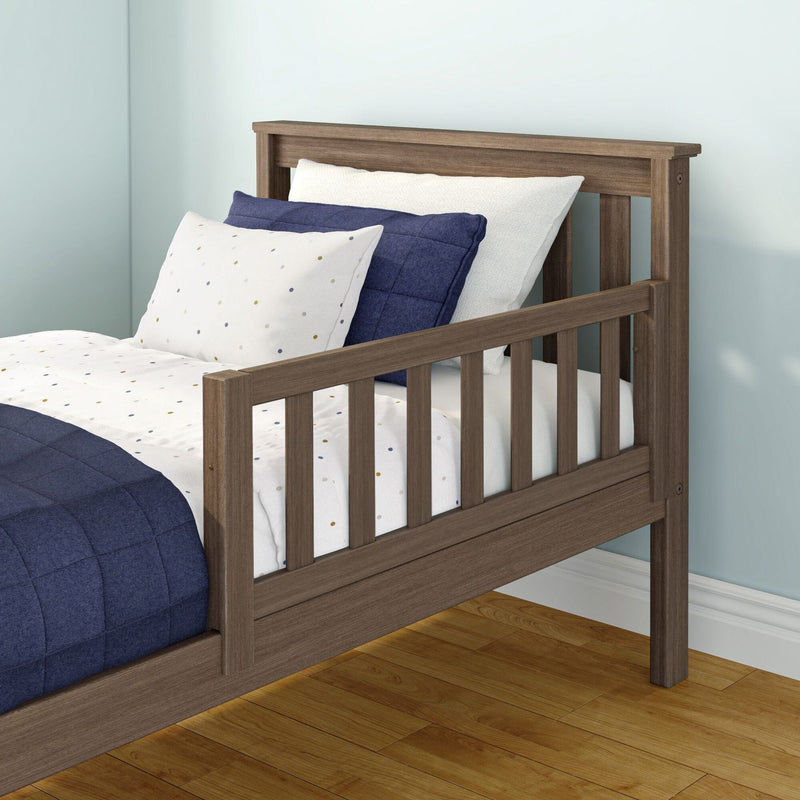 Brown wooden twin bed with slatted headboard and footboard, navy quilt and white polka-dot sheets in a light-blue kids bedroom