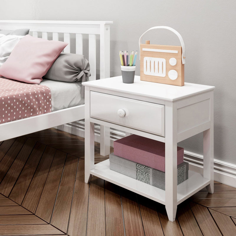 White nightstand bedside table in kids' pink-accented bedroom with polka-dot bedding, wooden toy radio, pencil cup and storage boxes on hardwood floor