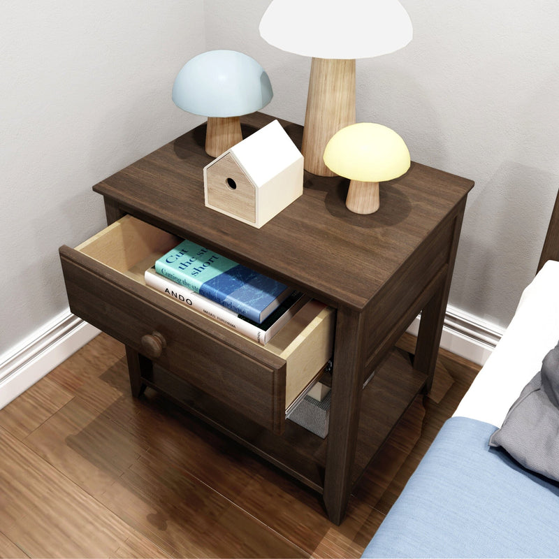 Dark wood nightstand with open drawer holding books, wooden birdhouse and mushroom-shaped lamps on hardwood bedroom floor beside bed