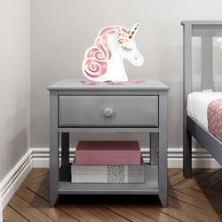 Gray bedside table with unicorn night light and books in a child's bedroom.
