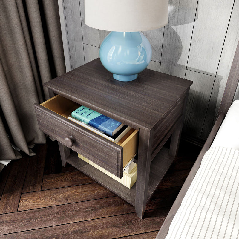 Modern rustic wooden nightstand with open drawer holding books, blue ceramic table lamp with white shade on hardwood bedroom floor