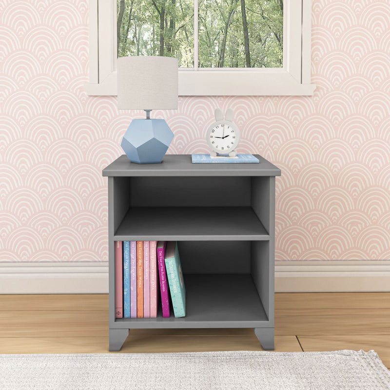 Gray nightstand with books, a geometric lamp, and clock, set against a patterned wallpaper, enhancing modern bedroom decor.