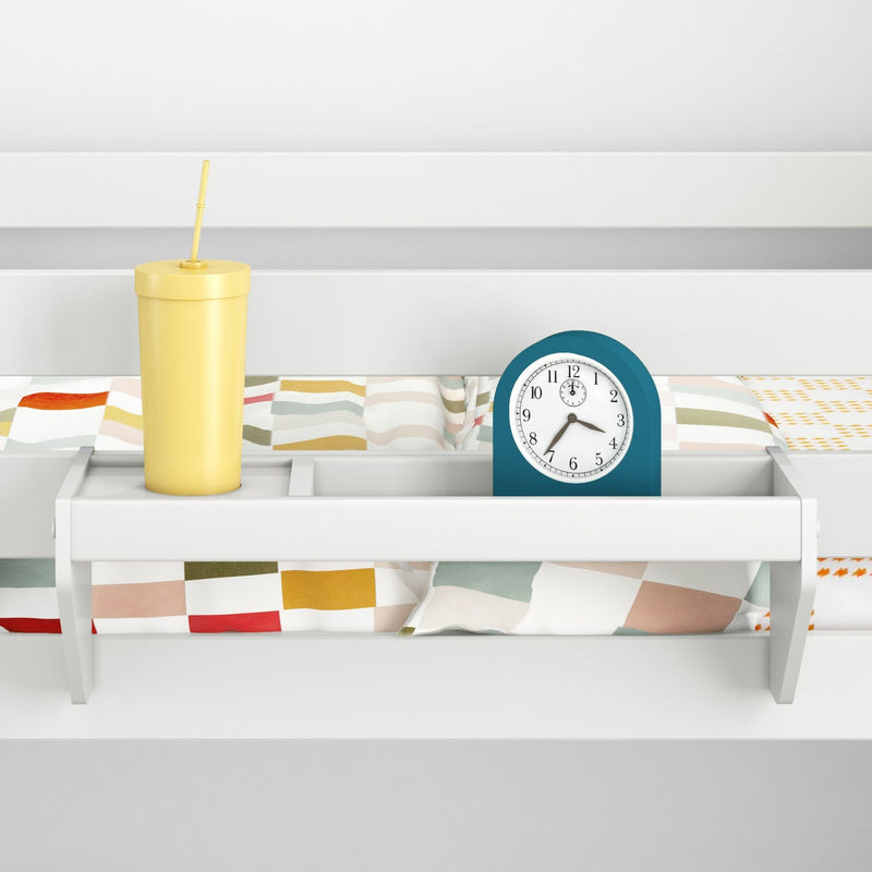 Bunk bed shelf organizer with yellow travel cup and teal alarm clock on colorful patterned children's bedding