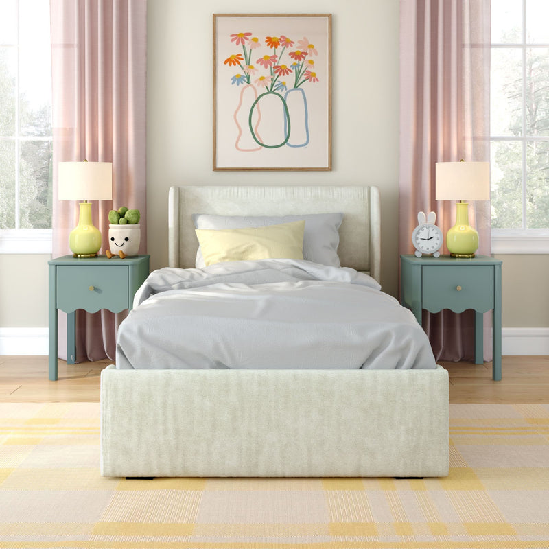 Modern pastel bedroom with upholstered bed, floral wall art, pink curtains, teal nightstands, yellow lamps, alarm clock and cozy bedding