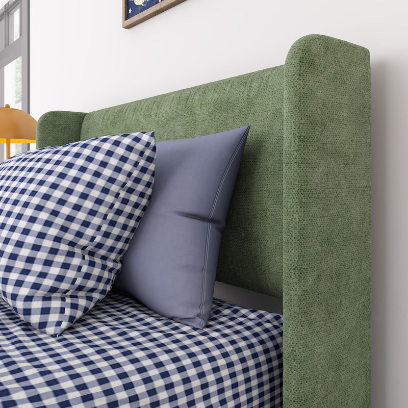 Green upholstered headboard with blue pillows and blue-and-white gingham bedding in a modern bedroom featuring a yellow bedside lamp