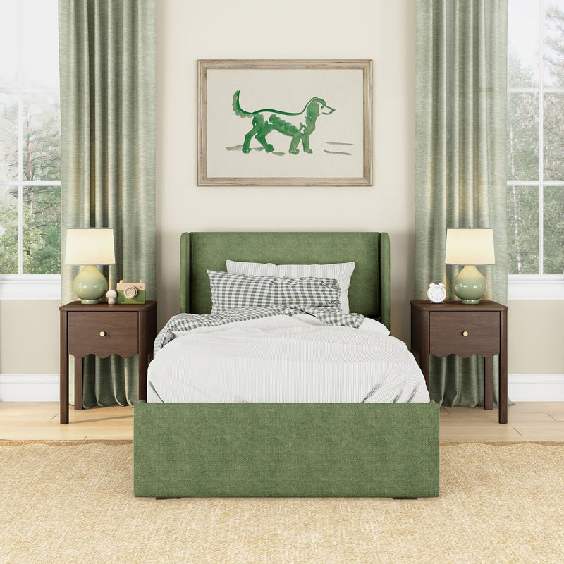 Green bedroom interior with upholstered green bed, gingham pillows and striped bedding, wood nightstands and lamps, framed green watercolor dog art and floor-length curtains by large windows