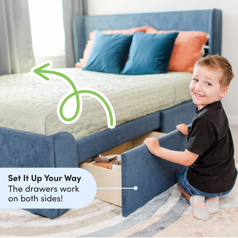Blue upholstered kids storage bed with pull-out under-bed drawers open, smiling boy demonstrating easy-access children's storage