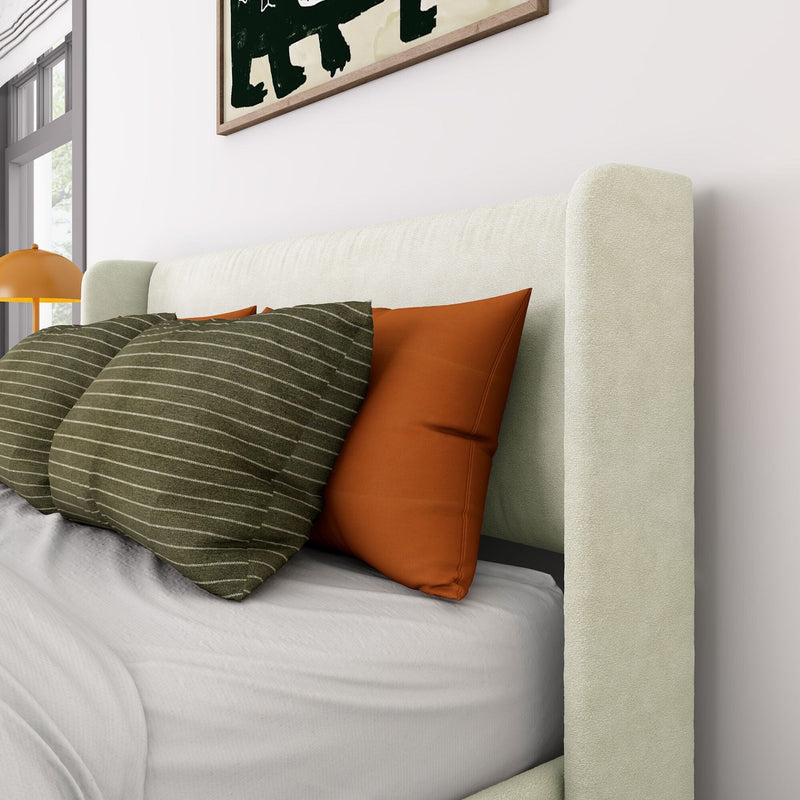 Modern bedroom close-up: beige upholstered headboard, rust-orange accent pillows, green striped cushions on white bedding, orange bedside lamp, minimalist framed wall art