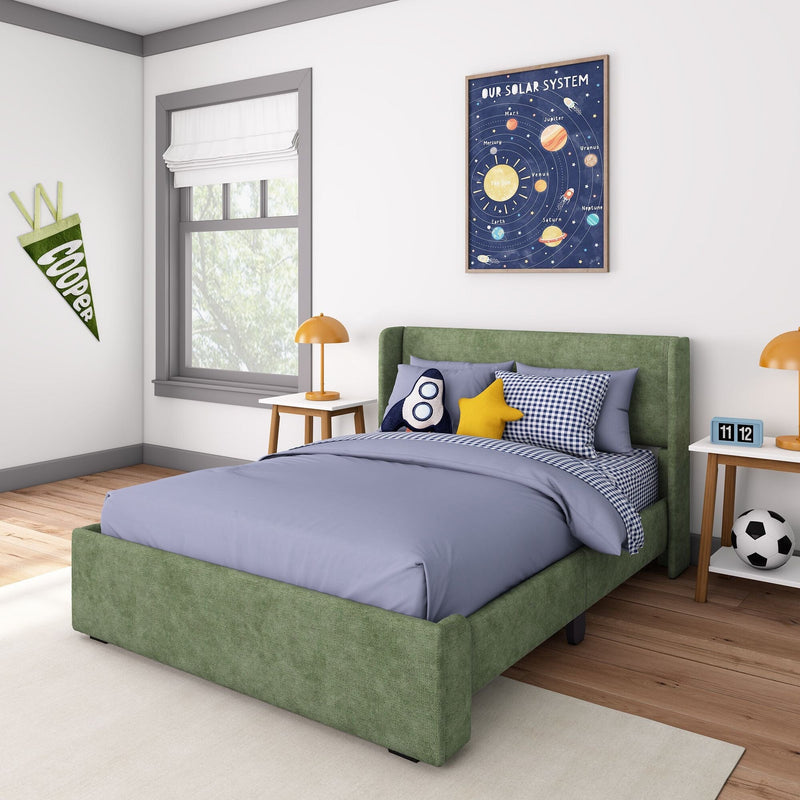 Children's bedroom with space-themed decor — green upholstered bed with rocket and star pillows, blue checkered bedding, wooden nightstand with orange lamp and flip alarm clock, framed solar system poster and Cooper pennant on wall, soccer ball on floor