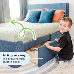 Child organizing toys in under-bed storage drawer of blue upholstered bed with versatile dual-sided access.