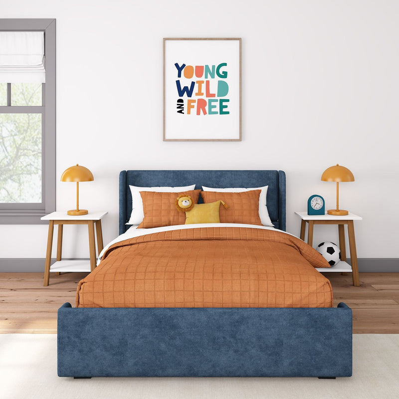 Kids bedroom decor: blue upholstered headboard, orange quilted bedding, plush lion toy, bedside lamps and "Young Wild and Free" framed wall art
