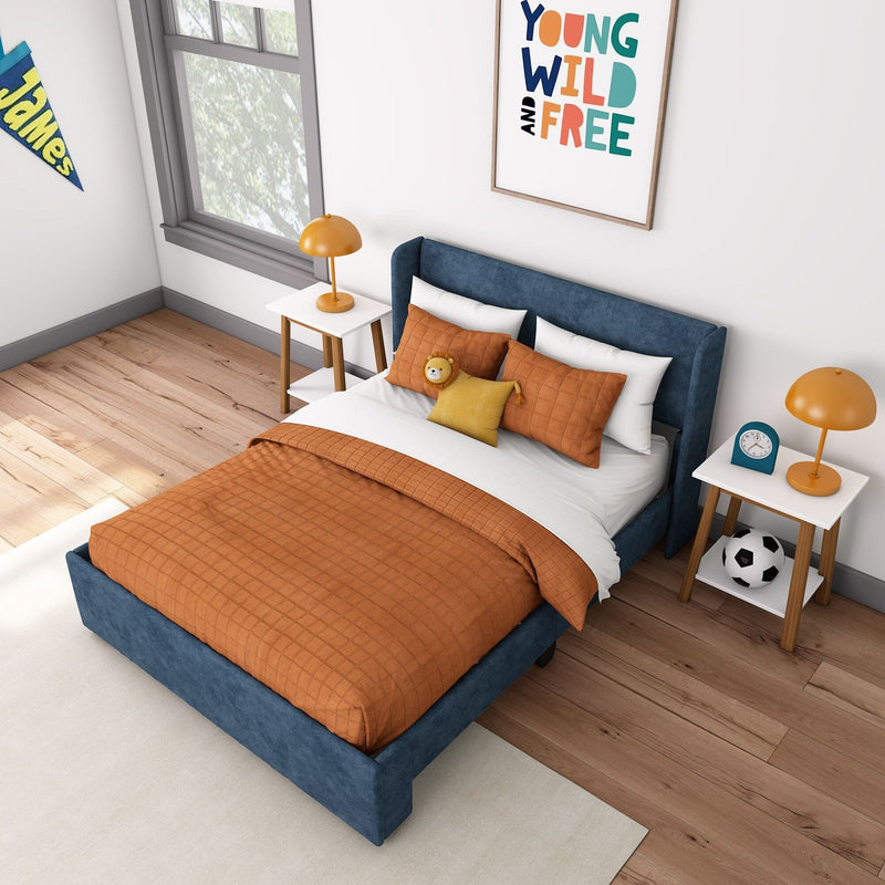 Child's modern bedroom with blue upholstered bed, orange quilt and pillows, matching bedside lamps, framed "Young Wild and Free" print and soccer ball on hardwood floor