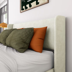 Stylish modern bed with green and orange decorative pillows, white bedding, and a textured beige headboard in a cozy bedroom setting.