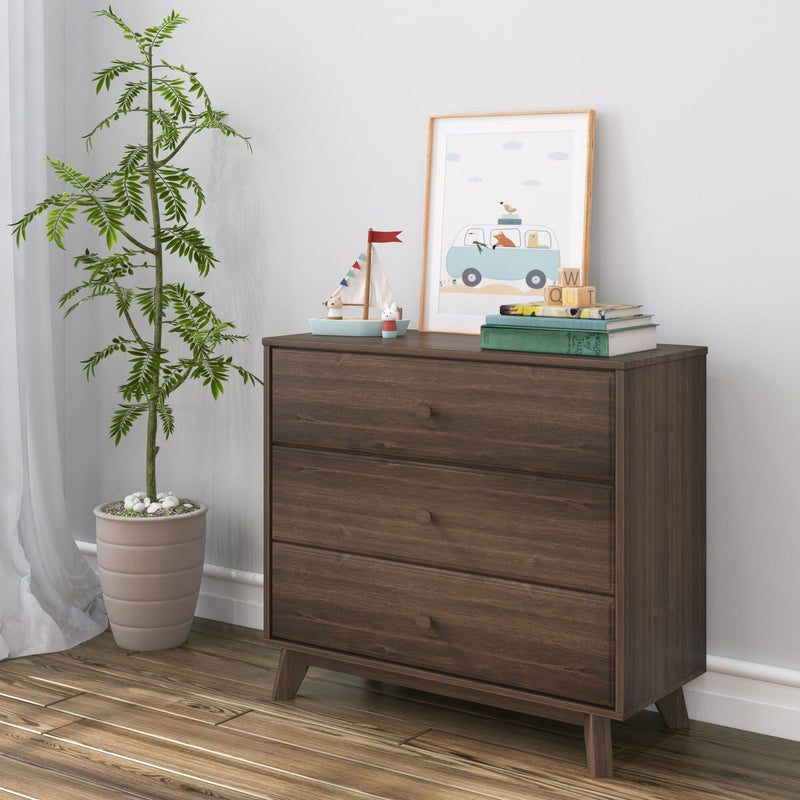 Dark walnut mid-century three-drawer dresser in a children's room nursery with potted plant, framed animal van print, toy sailboat, stacked books and wooden blocks