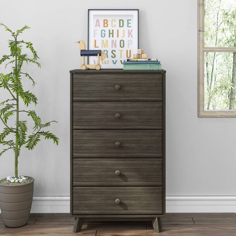 Tall five-drawer dark gray wooden dresser chest of drawers styled in a modern nursery or bedroom with a framed colorful alphabet print, wooden toy horse, stacked books and potted plant