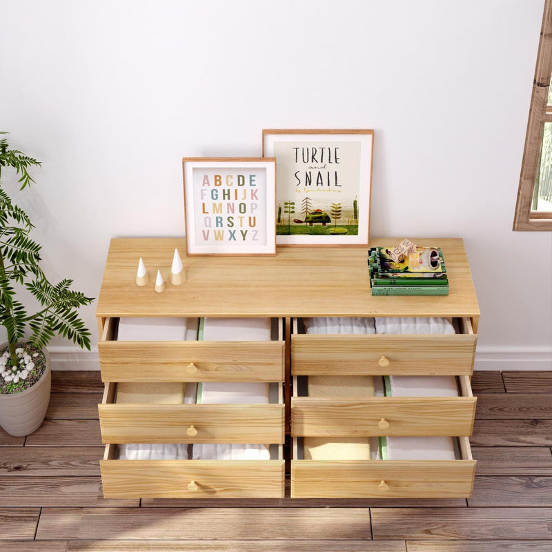 Pine six-drawer dresser in a children’s room with neatly folded clothes in open drawers, framed alphabet and turtle-and-snail prints, potted plant and toys on top