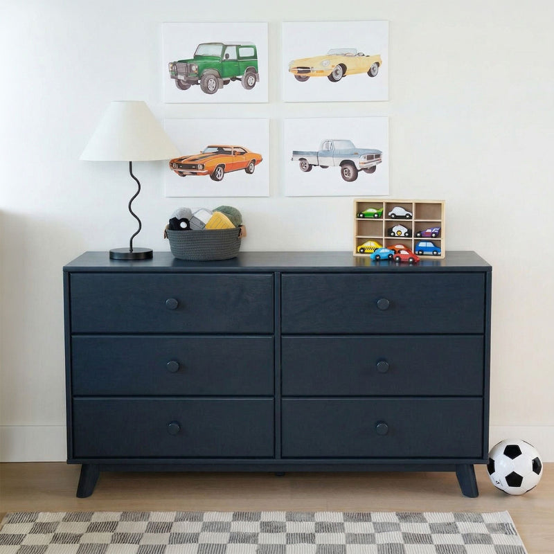 Navy blue dresser in kids' room with car wall art, wooden cubby of toy cars, woven storage basket, modern lamp and soccer ball — children's bedroom decor