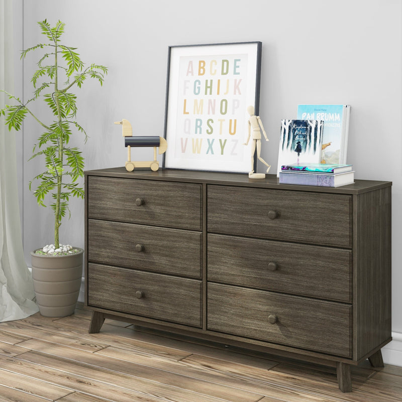 Dark wood six-drawer mid-century style dresser in nursery with colorful alphabet wall art, wooden toys, stacked books and a potted plant