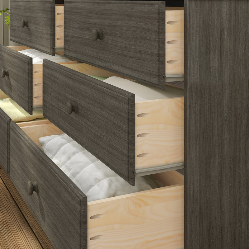 Dark gray wood dresser with multiple open drawers showing light plywood interiors and folded bedding on hardwood floor