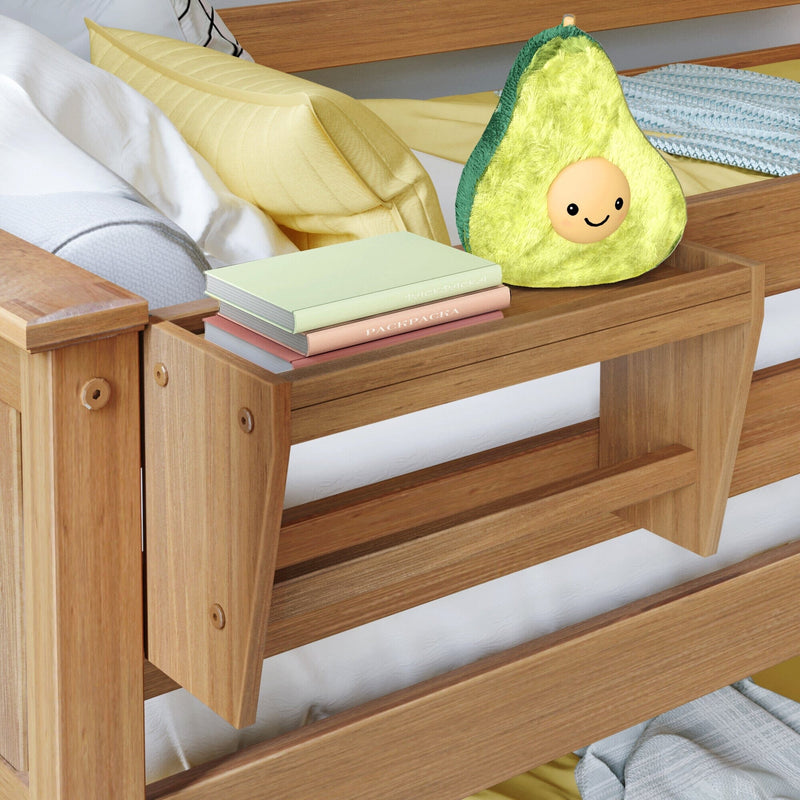Wooden bed with built-in bedside shelf holding a stack of pastel books and a smiling avocado plush pillow, cozy modern kids bedroom decor