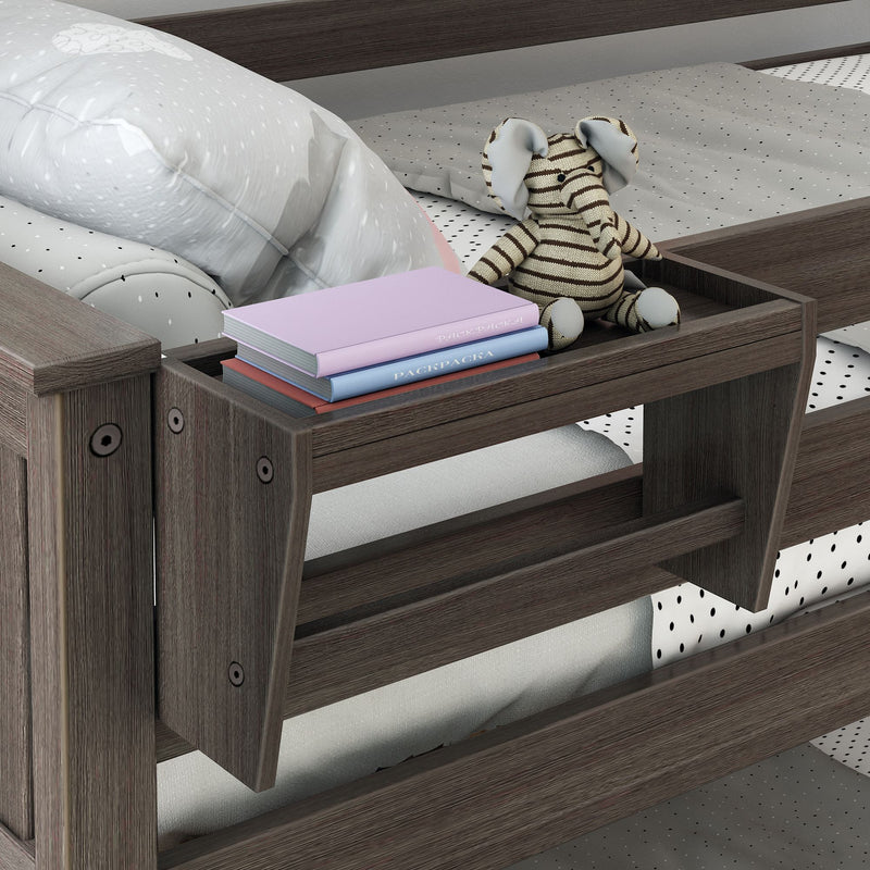 Grey wooden toddler bed with polka-dot bedding, striped elephant plush toy and stacked pastel children's books