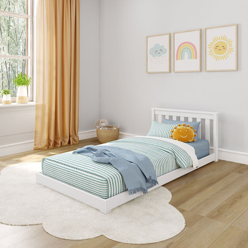 Kids bedroom with white low-profile toddler bed, teal striped bedding, blue throw, yellow sun plush, rainbow and sun wall art, golden curtains, round white rug on wood floor