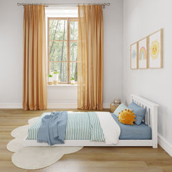 Minimalist children's bedroom with wooden floor, orange curtains, and a white bed featuring blue striped bedding and a smiling sun pillow.
