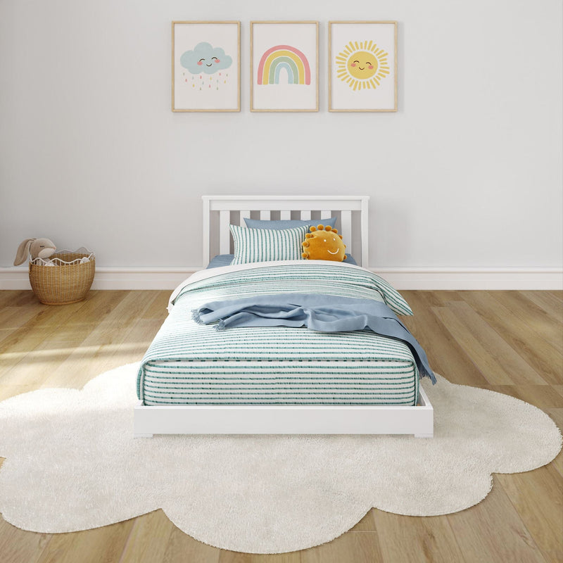 Minimalist nursery kids bedroom with white crib-style bed, striped bedding, plush sun pillow, rainbow and cloud wall art, wicker toy basket and cloud-shaped rug on light wood floor